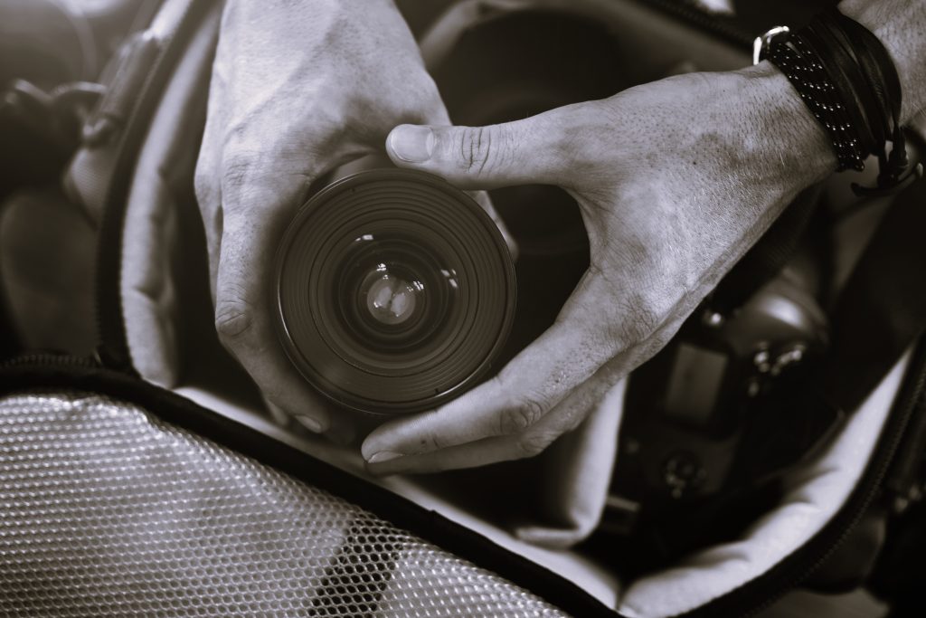 closeup hands getting camera lens from bag scaled
