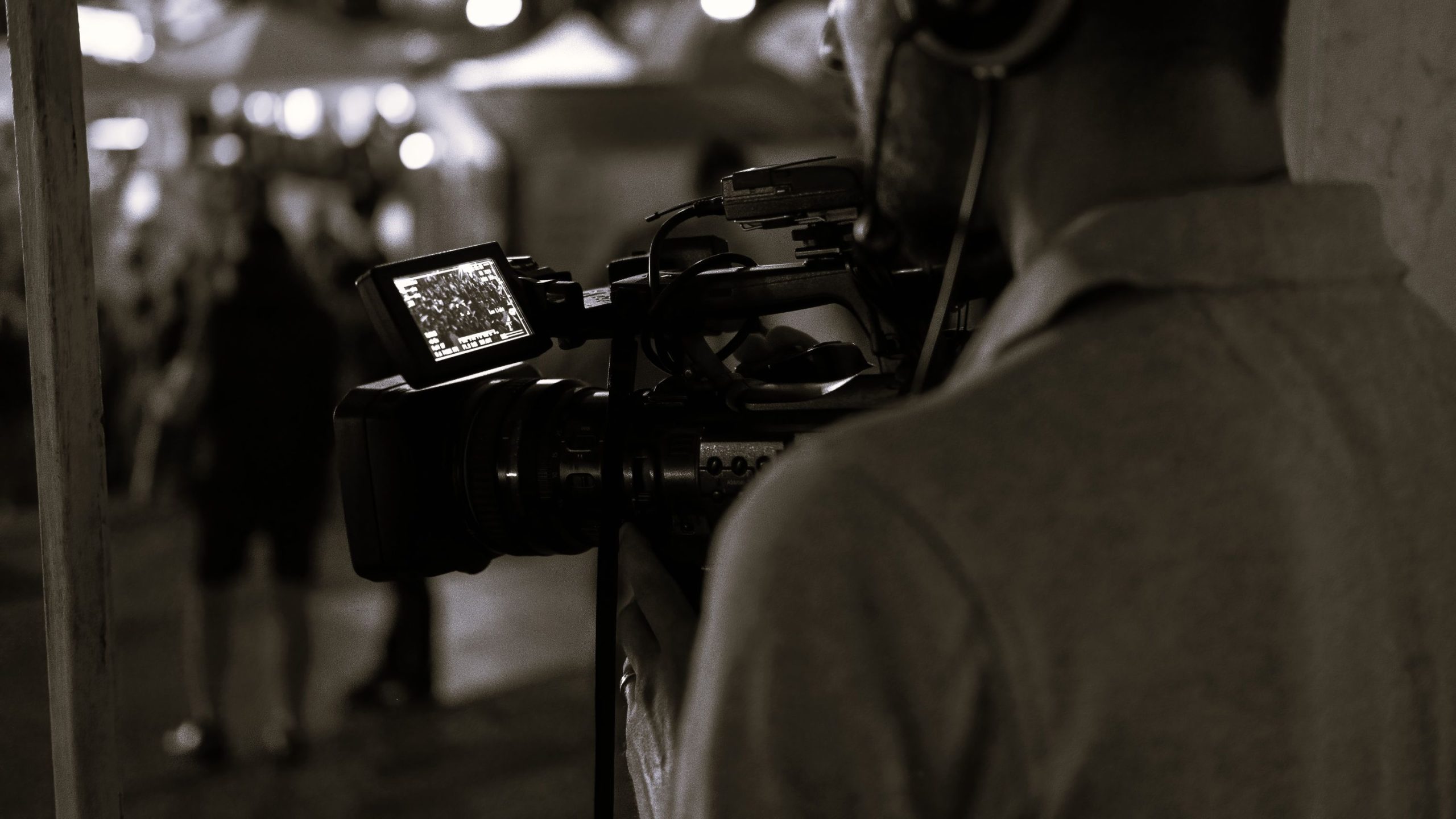 professional cameraman recording poeple watching football public place night scaled